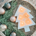 Load image into Gallery viewer, Christmas tree shaped candle burning on a rattan tray with Christmas ornament on it