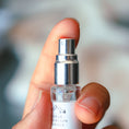 Load image into Gallery viewer, Small clear bottle with silver cap held by a hand against a blurred background