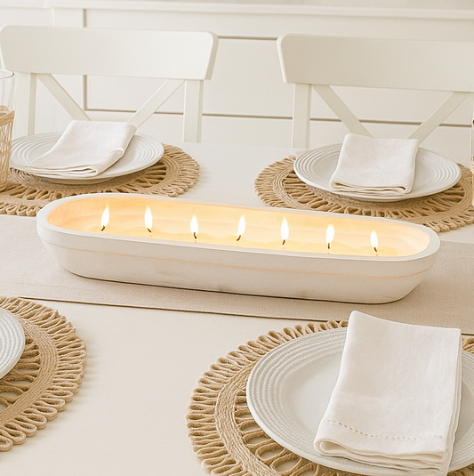 Dining table setting with candles, plates, and decorative items in a bright room.