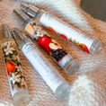 Load image into Gallery viewer, Three small bottles with floral and fruit designs on a textured fabric background
