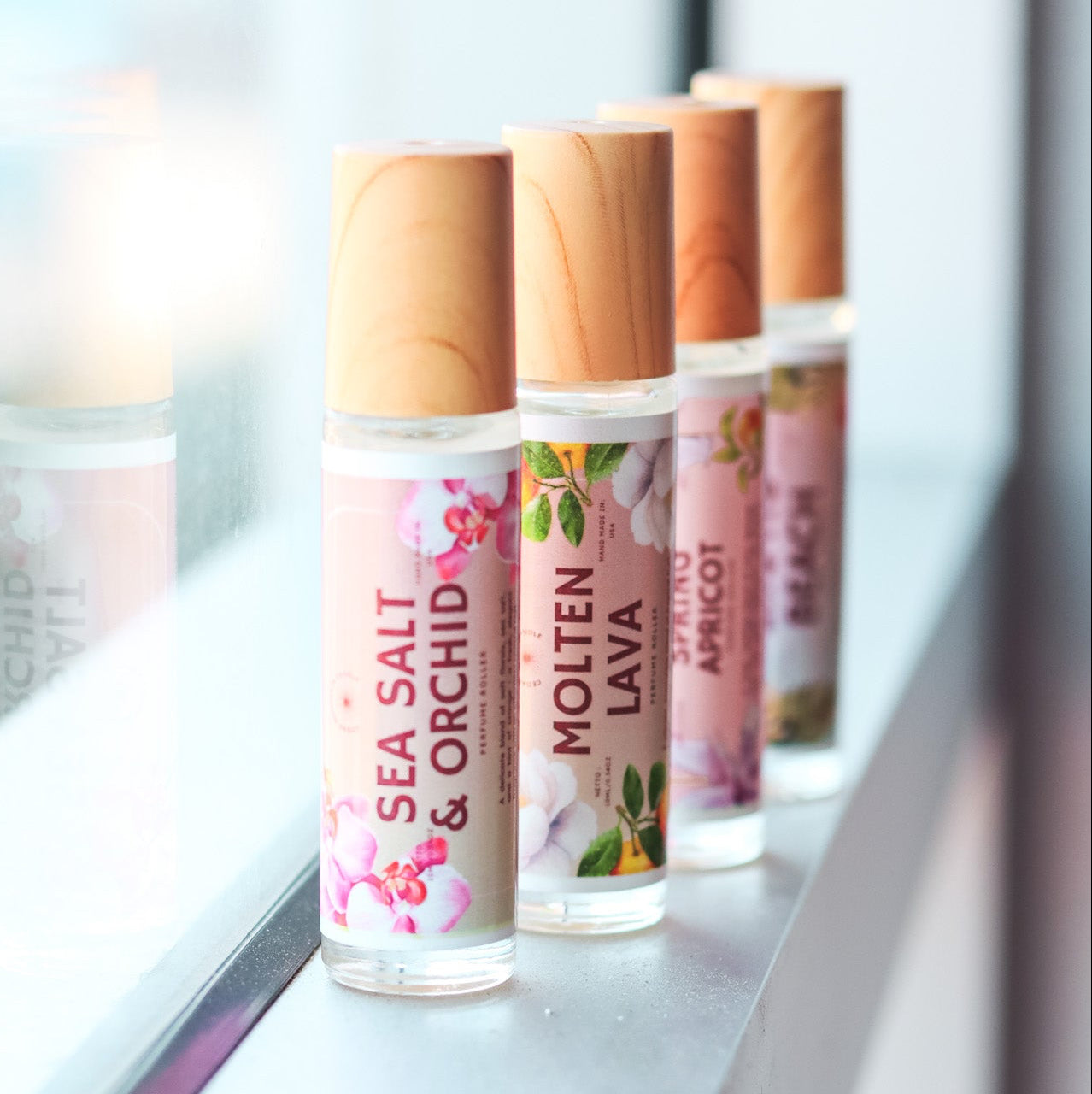 Row of perfume rollerball  tubes with wooden caps on a white surface.