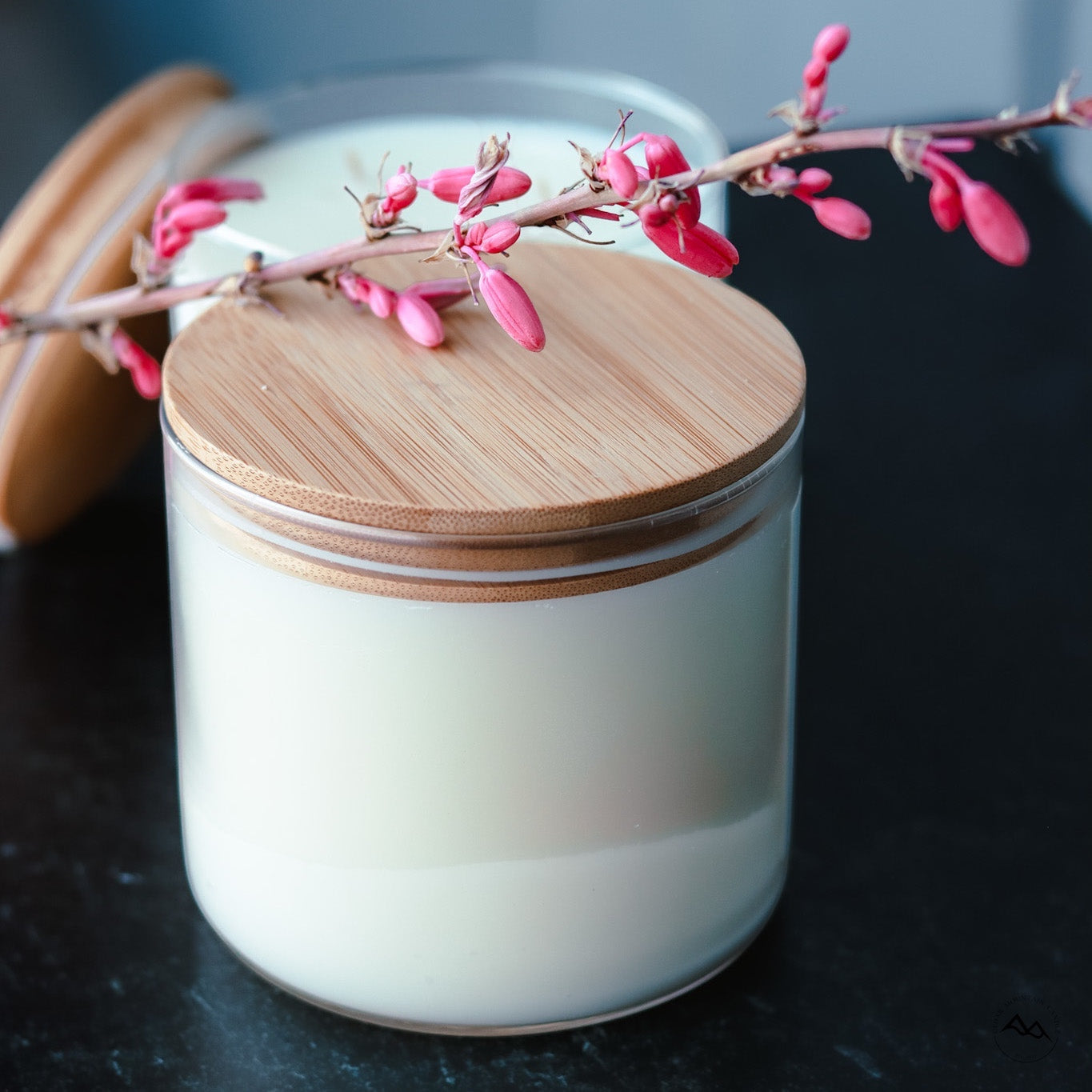 Cedar Mountain Candle 3-wick white soy wax candle in glass jar with bamboo lid, adorned with pink flowers.