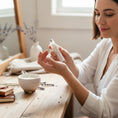 Load image into Gallery viewer, Cedar Mountain Candle woman applying exotic beach roll-on perfume oil with notes of pineapple, hibiscus, and coconut milk.
