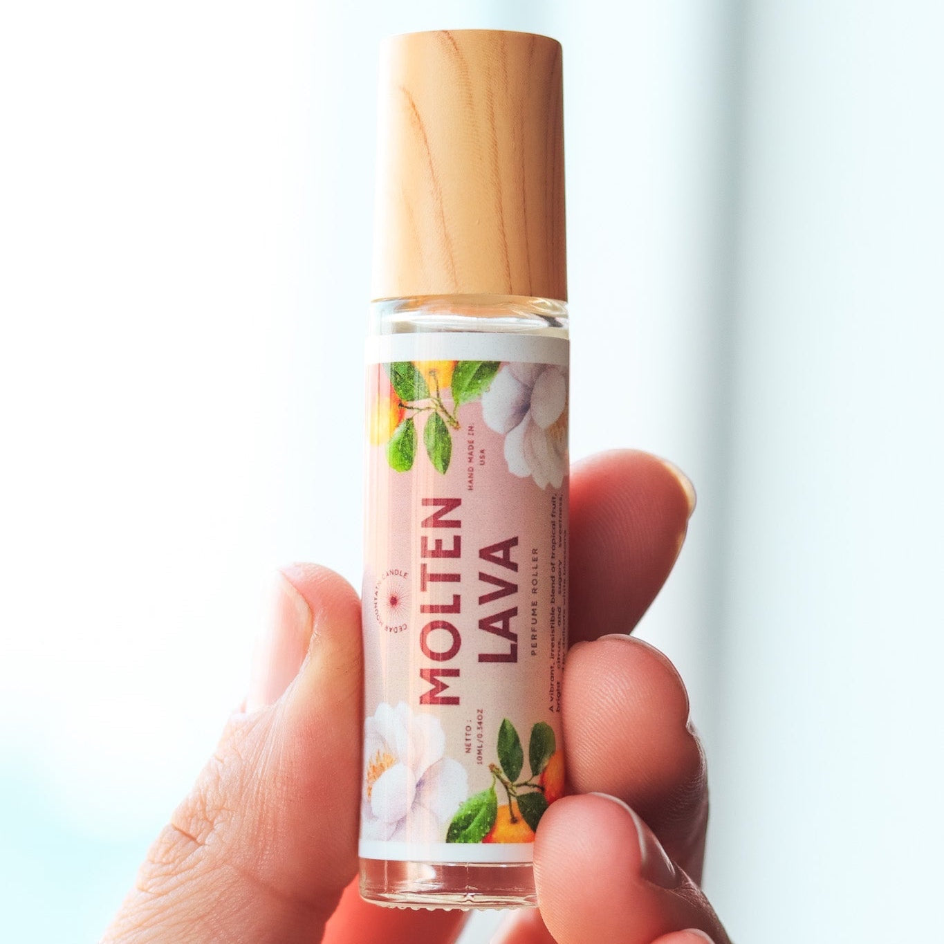 Cedar Mountain Candle Molten Lava roll-on perfume oil with tropical fruit and floral design. 10ml glass bottle with bamboo lid.