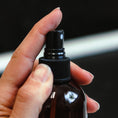 Load image into Gallery viewer, Cedar Mountain Candle 8 oz Starfruit & Mandarin room spray bottle being held and sprayed.
